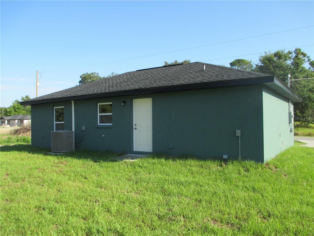 The exterior of a dark green, single-story house features a white door and two windows — 5762 NW 5TH STREET, OCALA, FL