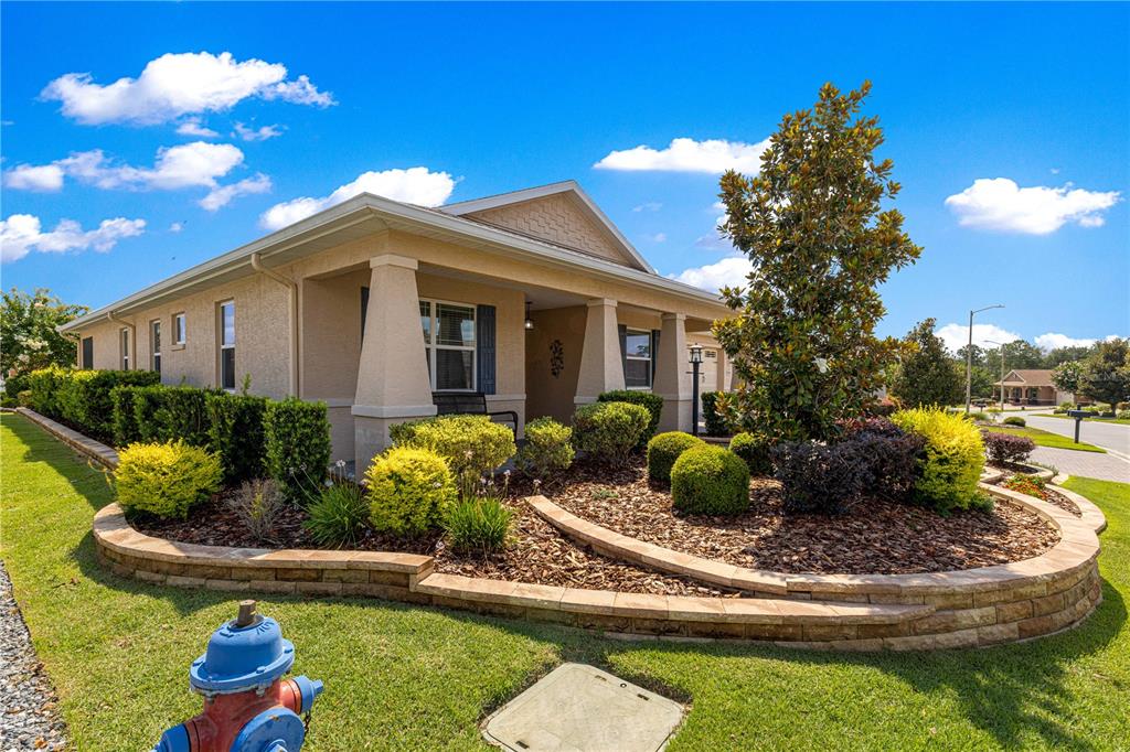 A single-story house with a tan exterior, front porch, and a landscaped garden bed — 9041 SW 88TH PLACE, OCALA, FL