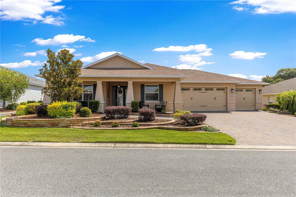 A single-story house with a tan stucco exterior, a paved driveway, and a landscaped front yard — 9041 SW 88TH PLACE, OCALA, FL