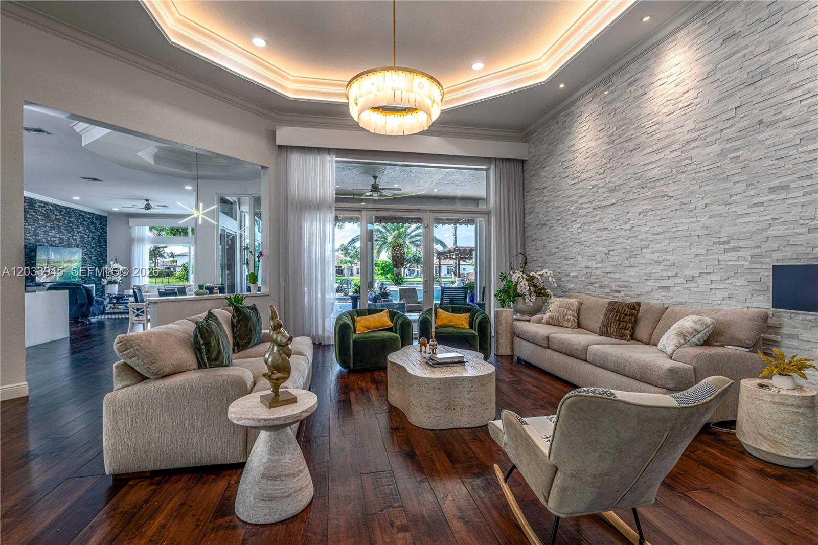 A living room features a stone accent wall, dark wood floors, and a tray ceiling — 15253 SW 40th St # 0, Davie FL 33331, DAVIE, FL
