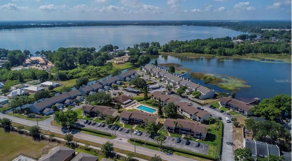 An aerial view shows a multi-building apartment complex situated next to a large lake — 900 AVENUE Z SE UNIT D6, WINTER HAVEN, FL