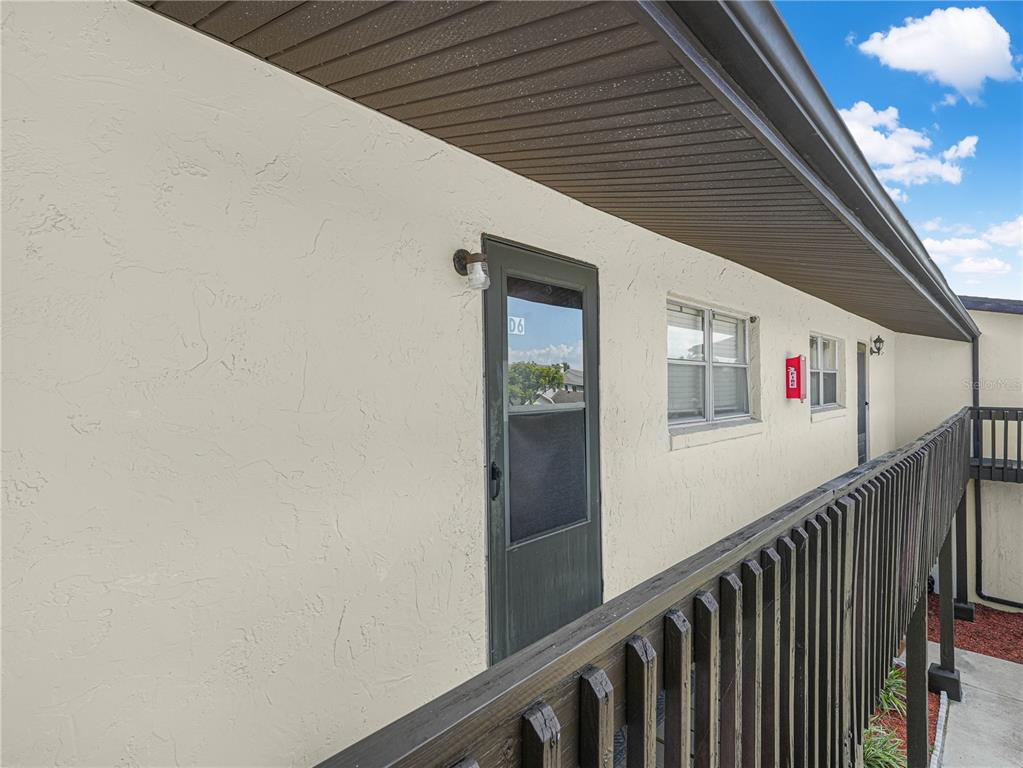 An exterior view of a second-story apartment balcony with a dark door labeled D6 — 900 AVENUE Z SE UNIT D6, WINTER HAVEN, FL