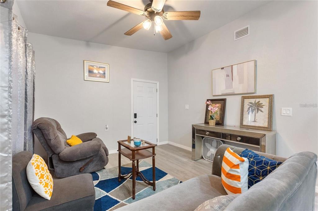 A living room features gray walls, a ceiling fan, a rug, and gray furniture — 1495 PENNIWA STREET, INTERCESSION CITY, FL