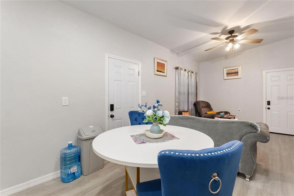A dining area with a round white table and blue chairs sits before a living room — 1495 PENNIWA STREET, INTERCESSION CITY, FL