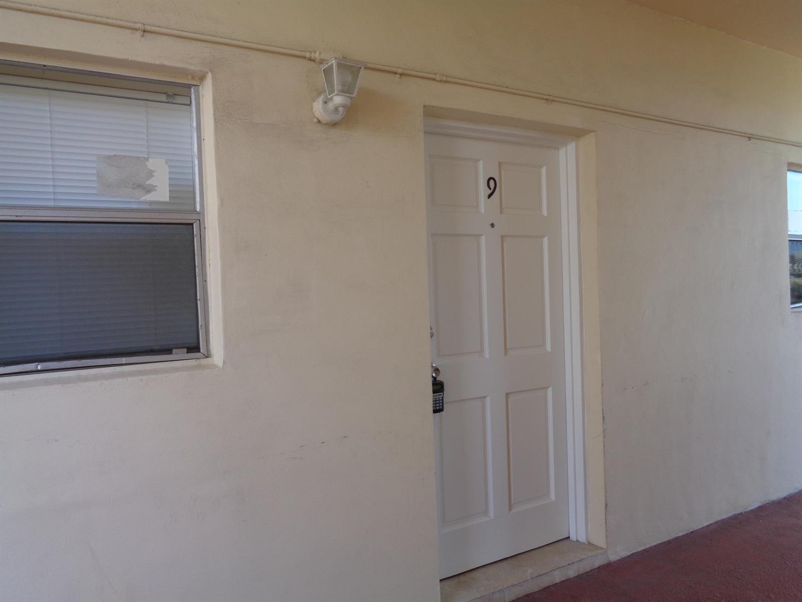 A white door marked with the number nine sits beside a window on a building — 2008 Jackson Street # E9, Hollywood FL 33020, HOLLYWOOD, FL