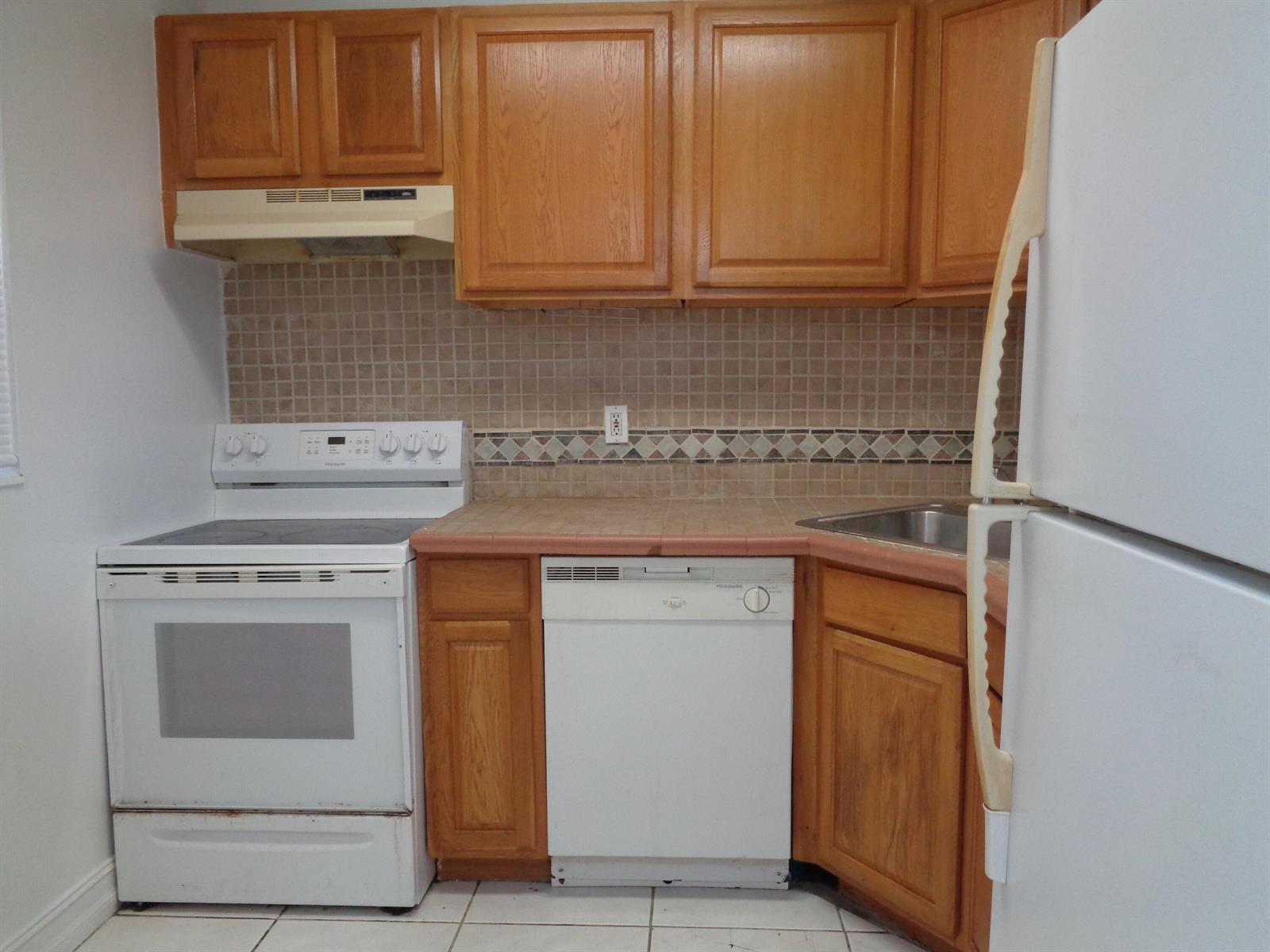A kitchen features wood cabinets, white appliances, a tiled backsplash, and a tiled countertop — 2008 Jackson Street # E9, Hollywood FL 33020, HOLLYWOOD, FL