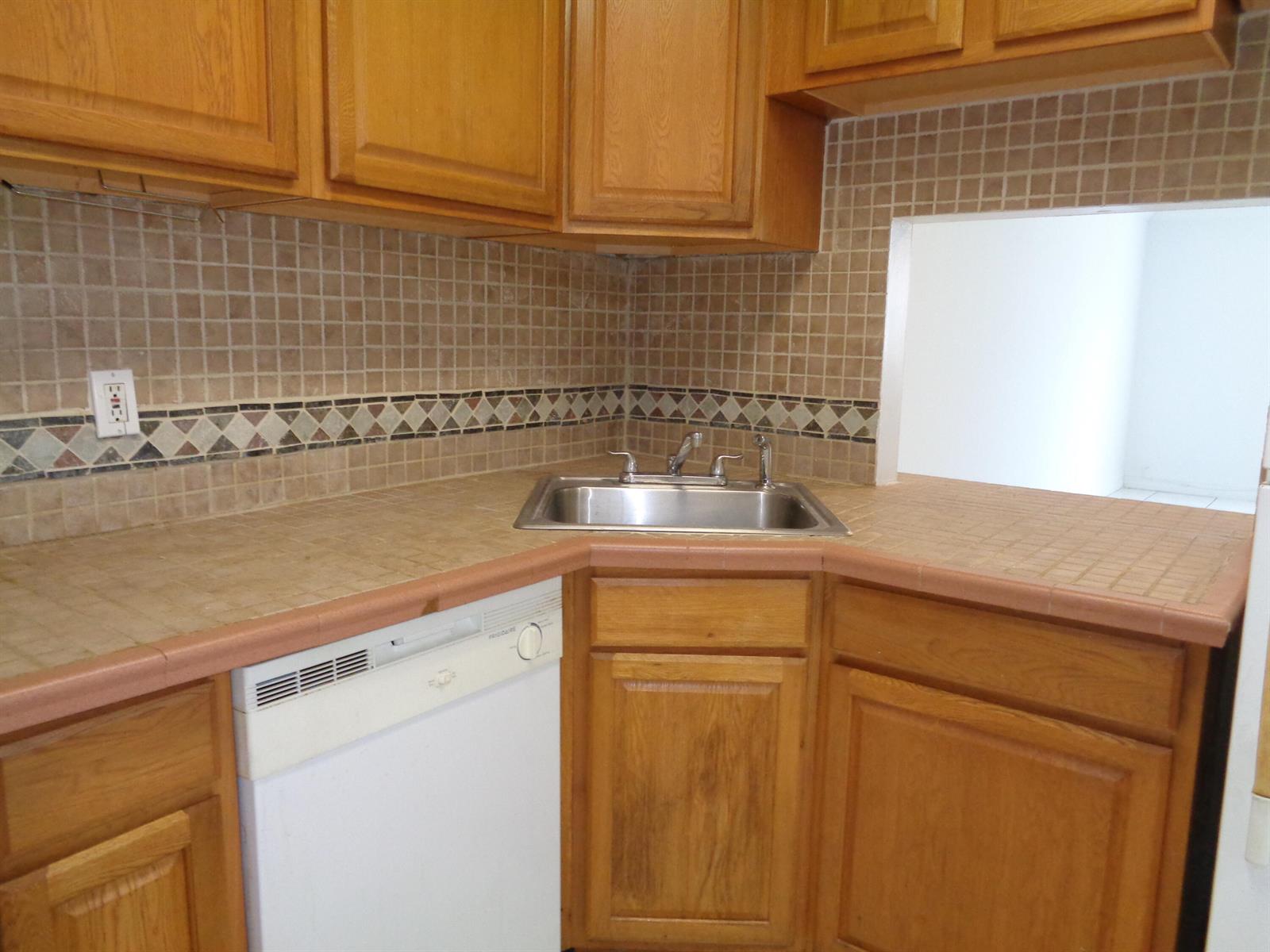 A kitchen features wood cabinets, a corner sink, a dishwasher, and tiled countertops and backsplash — 2008 Jackson Street # E9, Hollywood FL 33020, HOLLYWOOD, FL