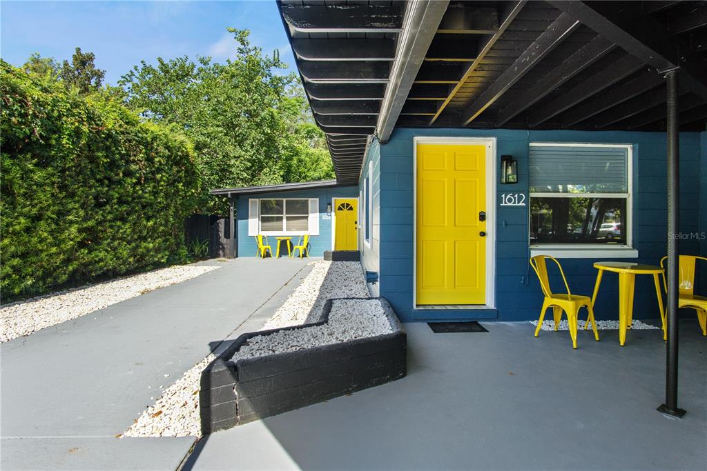 A blue exterior wall features a bright yellow door and a small outdoor seating area — 1612 & 1614 FERRIS AVENUE, ORLANDO, FL