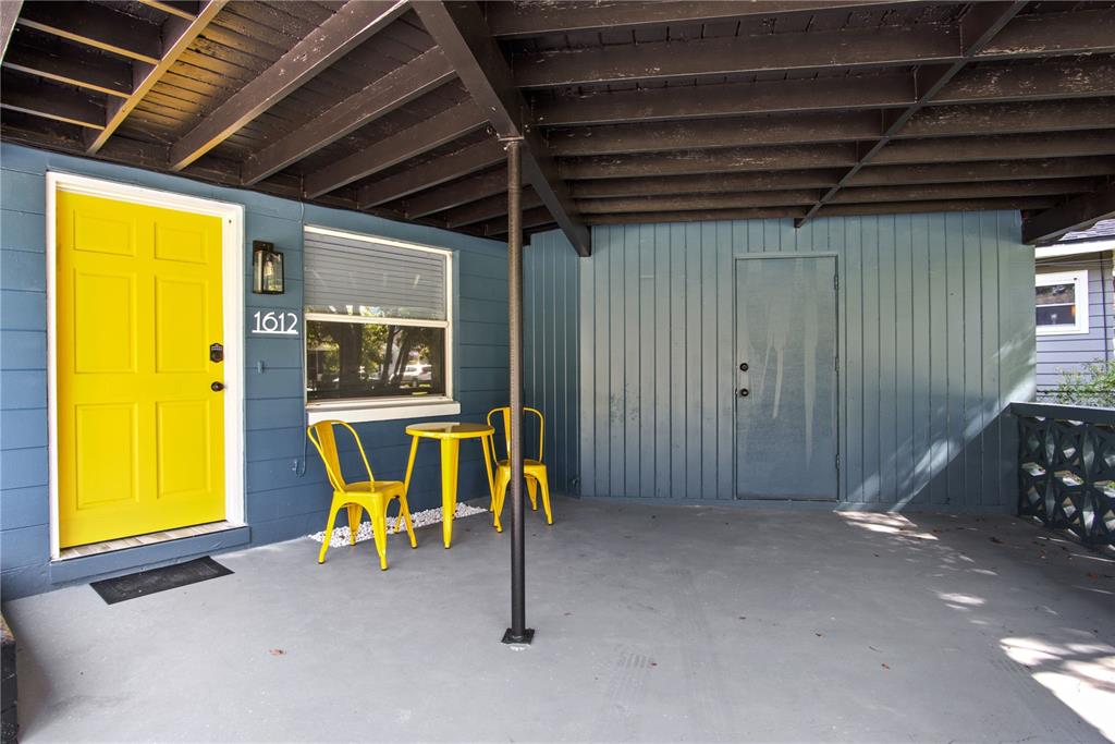 A covered porch features a bright yellow door, two yellow chairs, and a small table — 1612 & 1614 FERRIS AVENUE, ORLANDO, FL