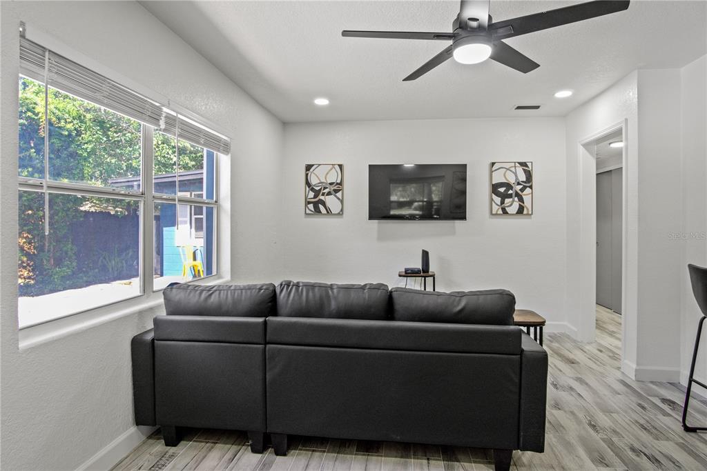 A living room features a black sectional sofa, a wall-mounted television, and wood-look flooring — 1612 & 1614 FERRIS AVENUE, ORLANDO, FL