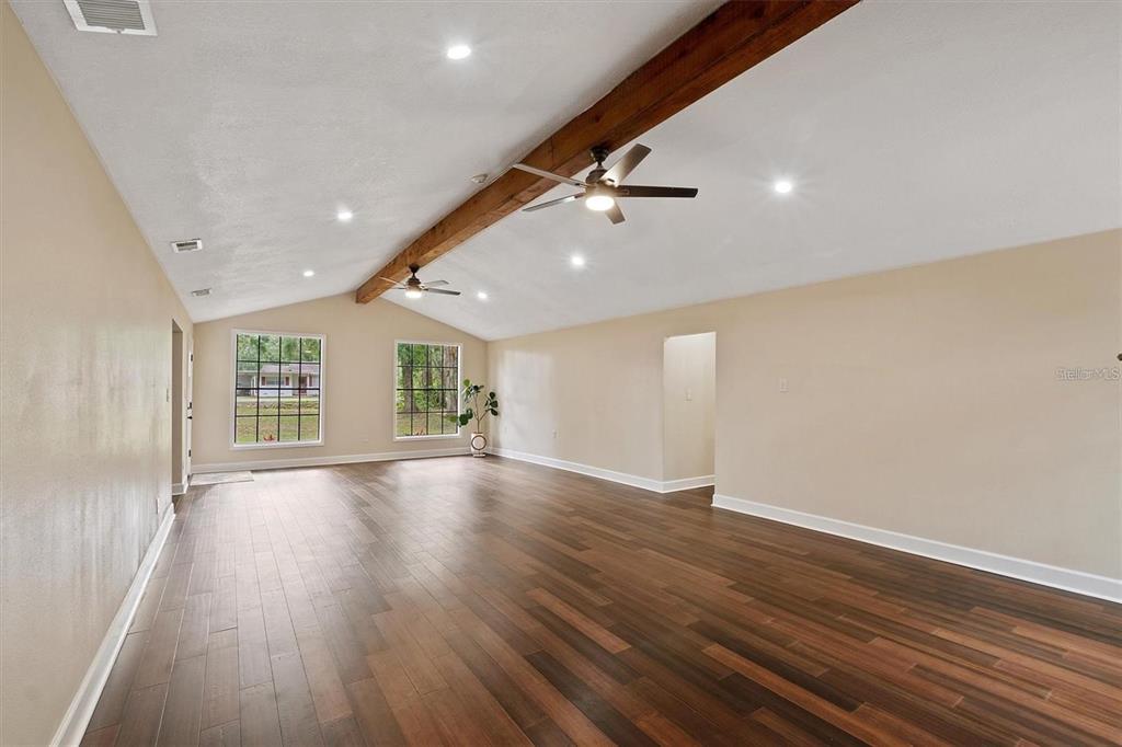 A spacious living room features vaulted ceilings, a wooden beam, and dark wood flooring — 6005 IKE SMITH ROAD, PLANT CITY, FL