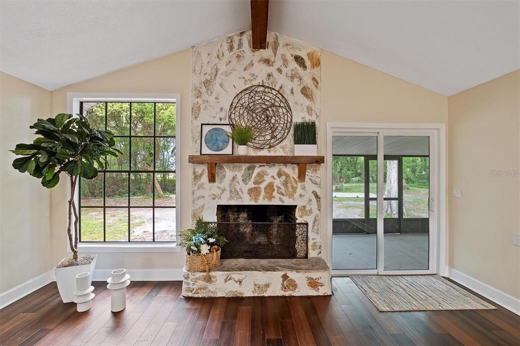 A living room features a stone fireplace, dark wood floors, and a large window — 6005 IKE SMITH ROAD, PLANT CITY, FL