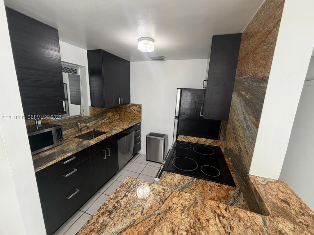 A kitchen features dark cabinets, granite countertops, and stainless steel appliances — 641 Espanola Way # 3, Miami Beach FL 33139, MIAMI BEACH, FL