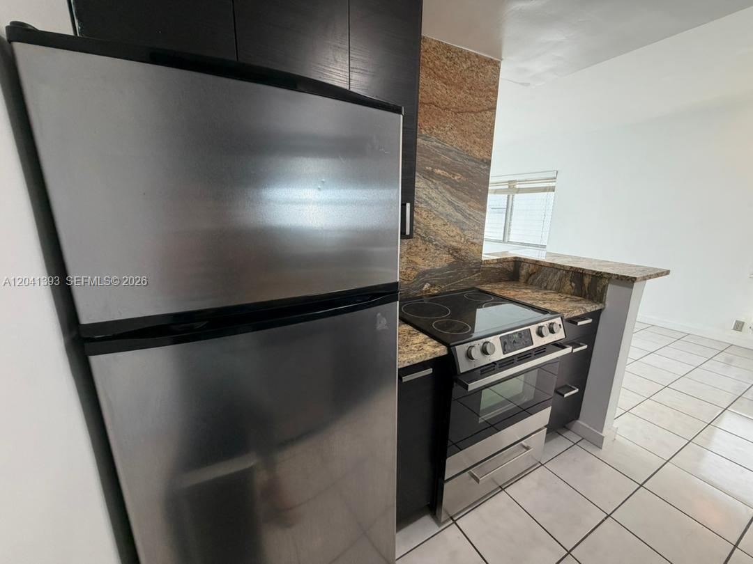 A kitchen features dark cabinets, stainless steel appliances, and granite countertops with a matching backsplash — 641 Espanola Way # 3, Miami Beach FL 33139, MIAMI BEACH, FL