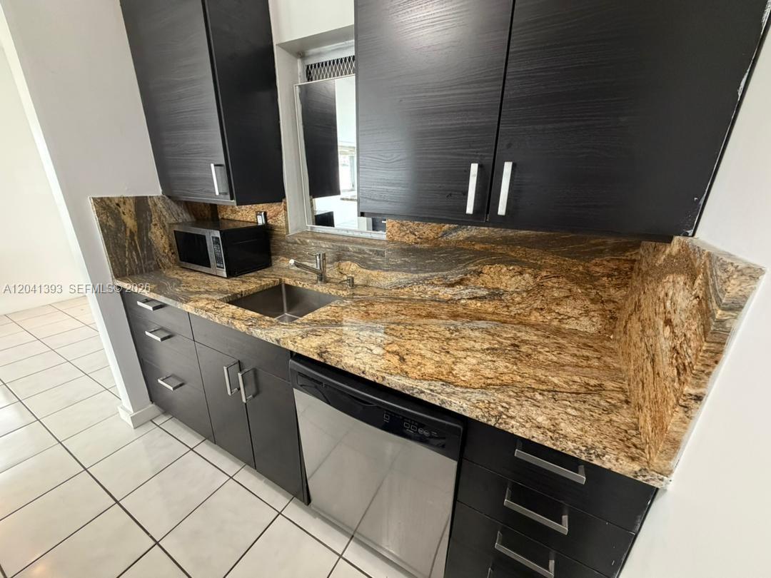 A kitchen features dark wood cabinets, granite countertops, a stainless steel sink, and a dishwasher — 641 Espanola Way # 3, Miami Beach FL 33139, MIAMI BEACH, FL