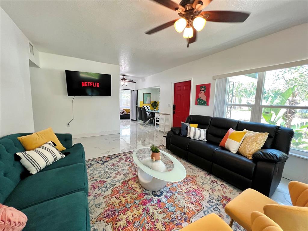 A living room features a teal sofa, a black leather sofa, and a patterned area rug — 2173 RIVIERA DRIVE, CLEARWATER, FL