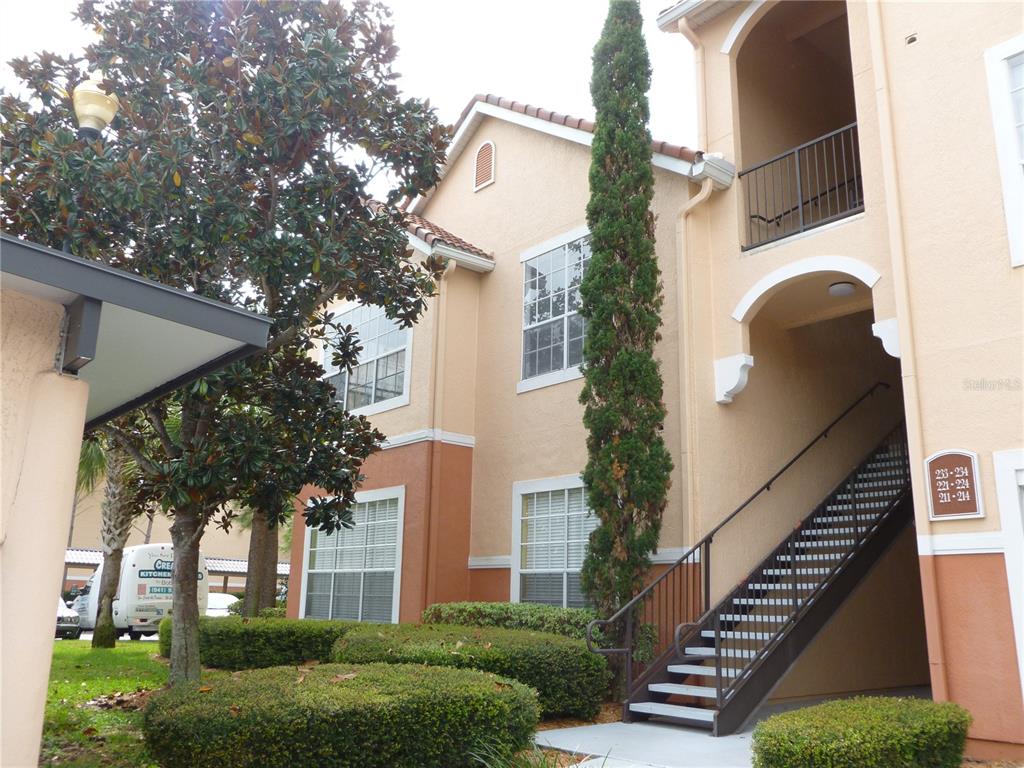 An exterior view of a two-story apartment building with stairs leading to upper units — 4174 CENTRAL SARASOTA PARKWAY UNIT 221, SARASOTA, FL