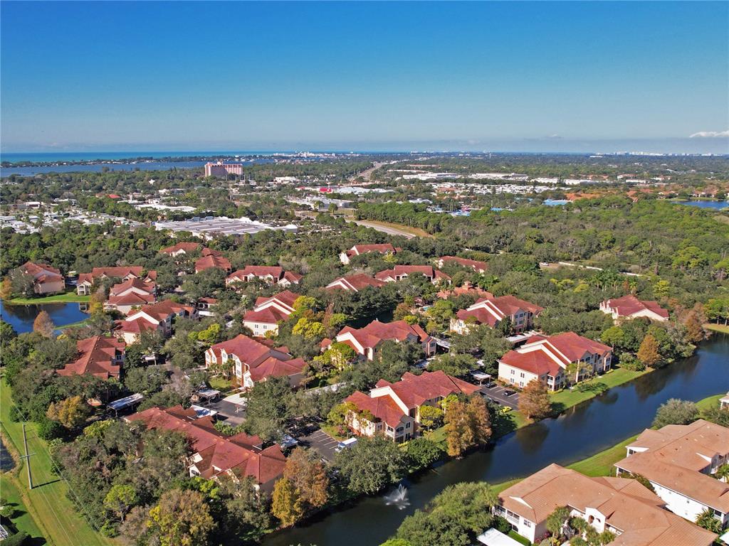 An aerial view shows a residential complex with multiple buildings, a canal, and surrounding greenery — 4174 CENTRAL SARASOTA PARKWAY UNIT 221, SARASOTA, FL