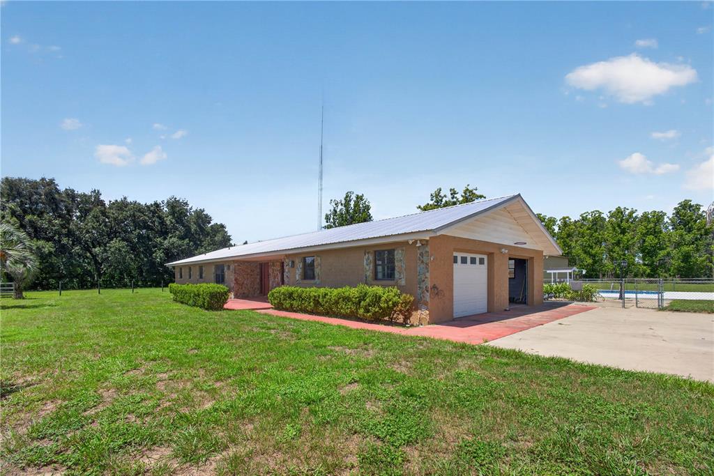 A single-story house with a metal roof, stucco exterior, and an attached two-car garage — 12776 SE 87TH TERRACE, BELLEVIEW, FL
