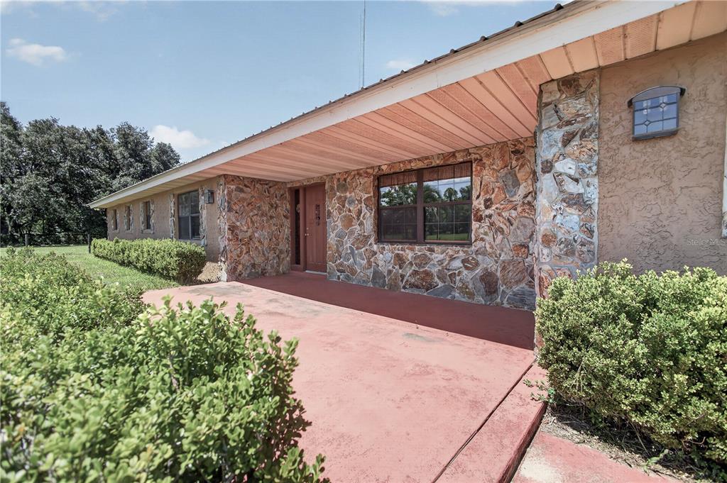 A ranch-style house exterior features a stone facade, a covered porch, and mature landscaping — 12776 SE 87TH TERRACE, BELLEVIEW, FL