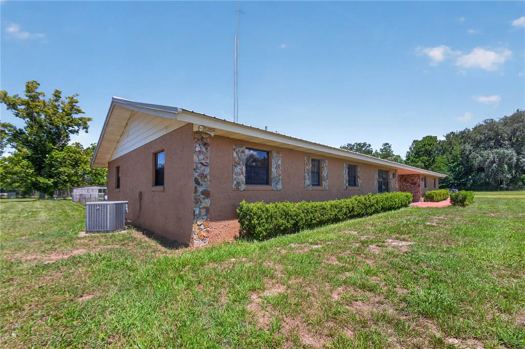 A single-story house with tan stucco walls, stone accents, and a metal roof — 12776 SE 87TH TERRACE, BELLEVIEW, FL