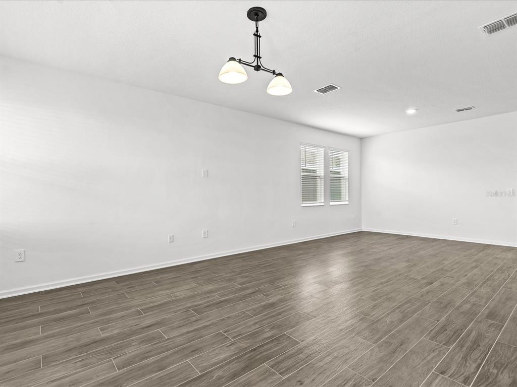 An empty room features white walls, a modern light fixture, and gray wood-look tile flooring — 2952 ARMSTRONG AVENUE, CLERMONT, FL