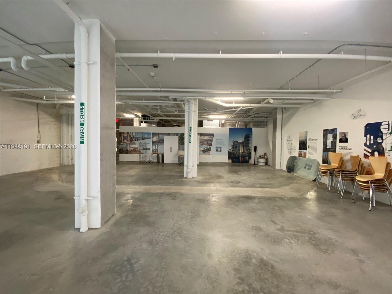 An unfinished commercial space features exposed ceiling pipes, concrete floors, and a structural support column — 1215 West Ave # 1, Miami Beach FL 33139, MIAMI BEACH, FL
