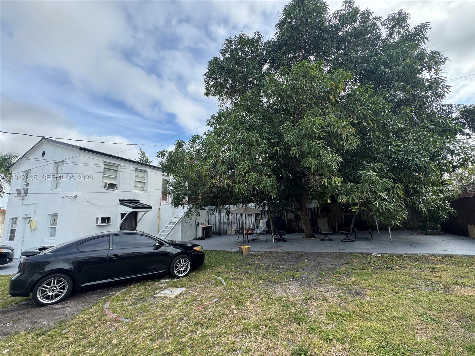 A black car is parked on a lawn next to a white house and tree — 921 N 17th Ct # 925, Hollywood FL 33020, HOLLYWOOD, FL