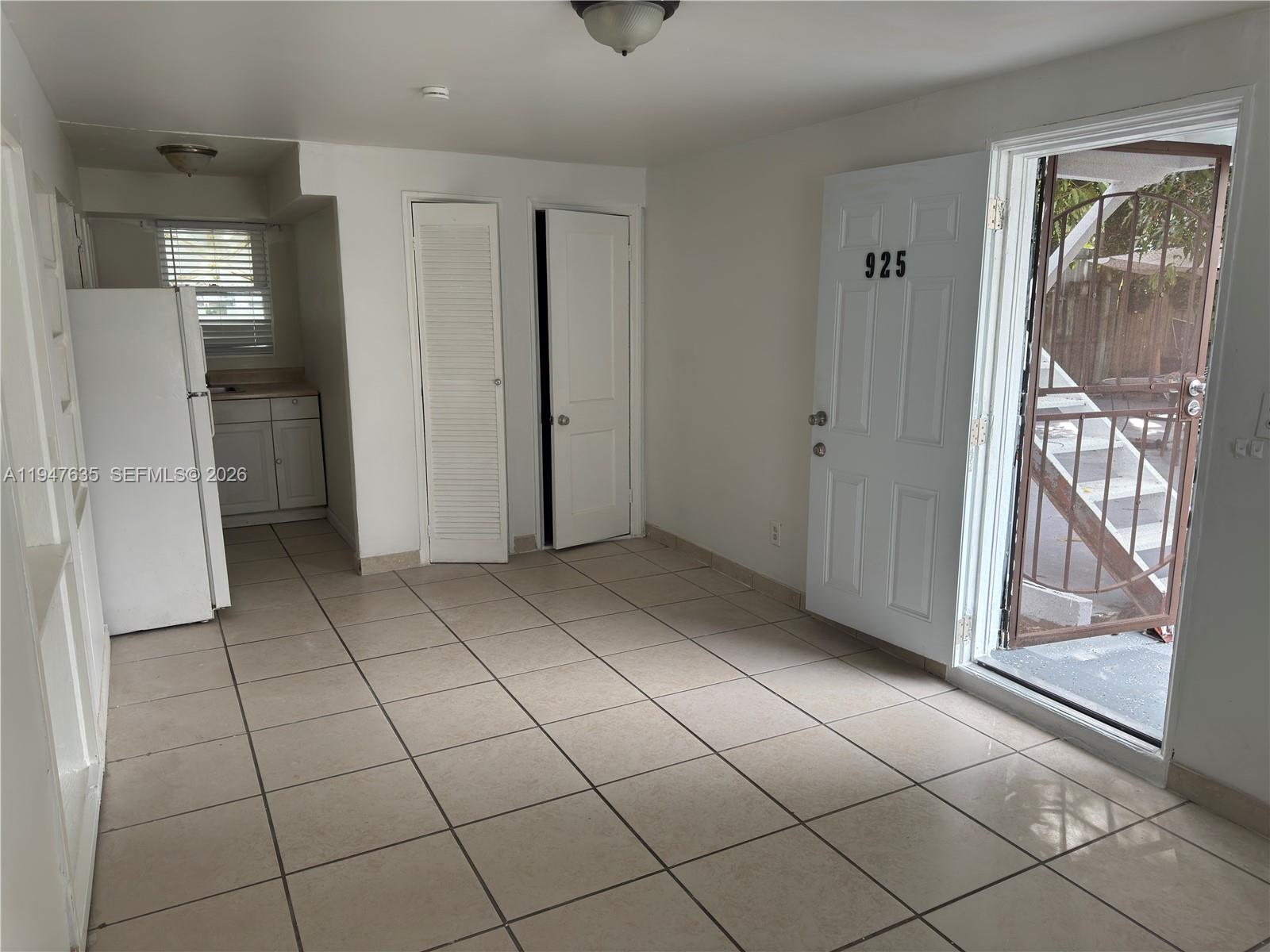A tiled room features a small kitchen area, two closed doors, and an open exterior door — 921 N 17th Ct # 925, Hollywood FL 33020, HOLLYWOOD, FL
