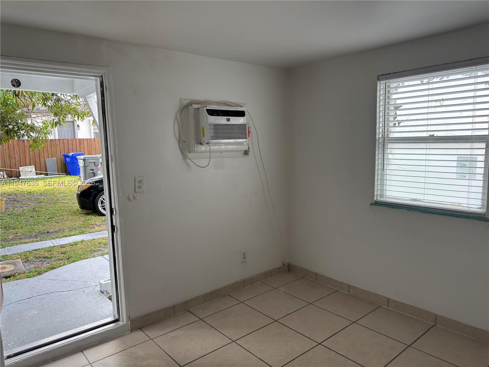 A room with tiled floors, a window with blinds, and a wall-mounted air conditioner — 921 N 17th Ct # 925, Hollywood FL 33020, HOLLYWOOD, FL