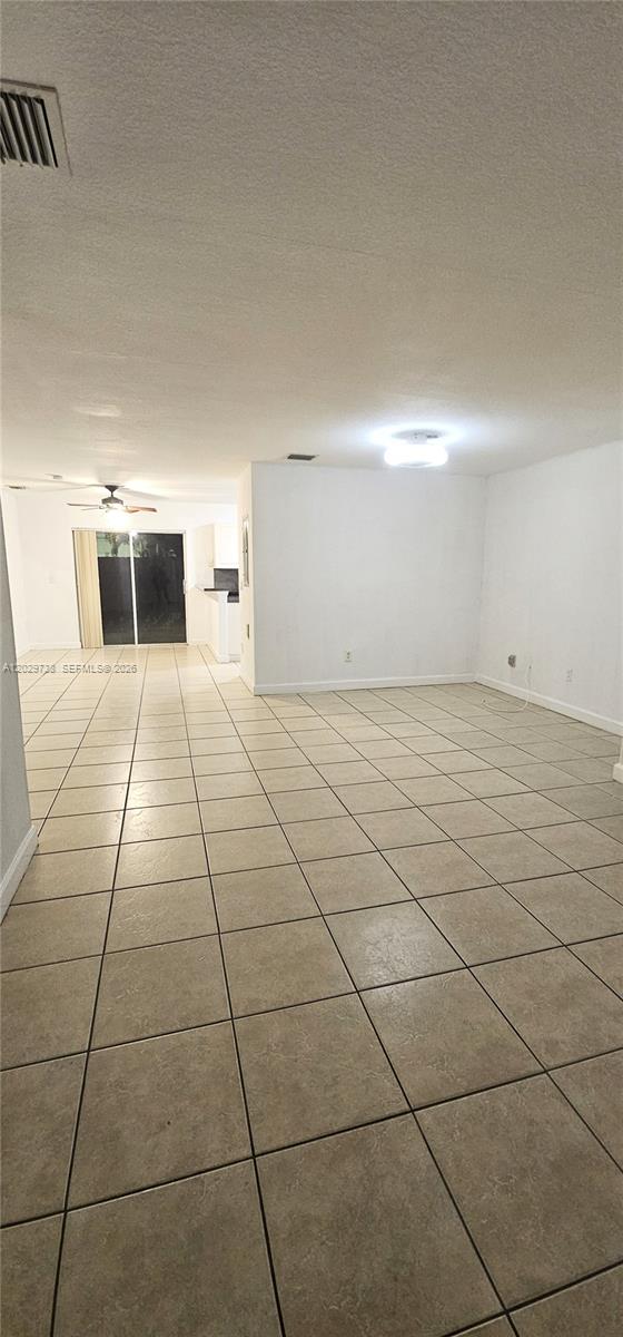 An open-concept living area features light-colored floor tiles, white walls, and a sliding glass door — 7309 NW 173rd Dr # 104, Miami FL 33015, MIAMI, FL