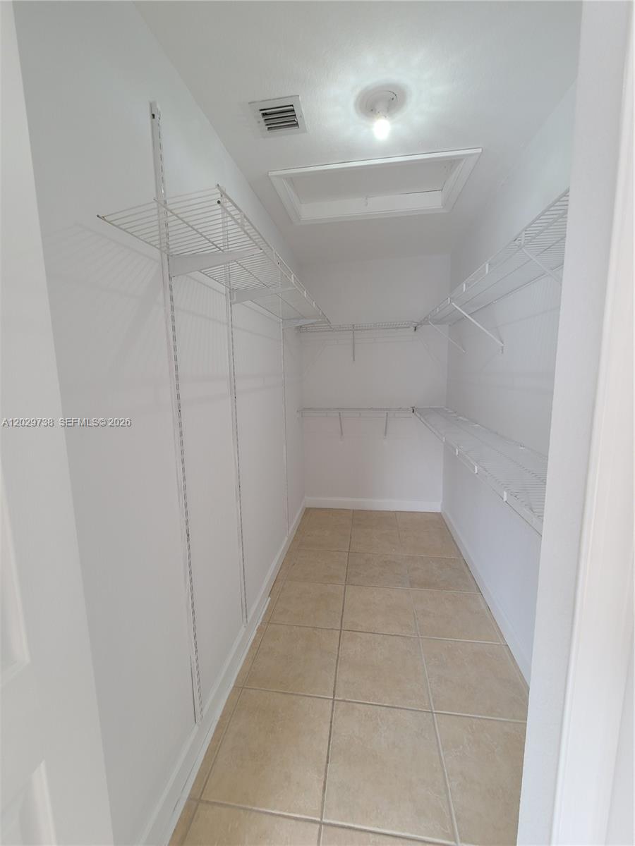 A walk-in closet features white wire shelving, tiled flooring, and a ceiling access panel — 7309 NW 173rd Dr # 104, Miami FL 33015, MIAMI, FL