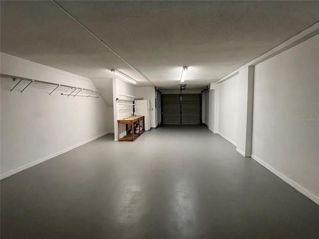 A long, empty garage with gray painted floors, white walls, and overhead fluorescent lighting — 751 PINELLAS BAYWAY S UNIT 305, TIERRA VERDE, FL