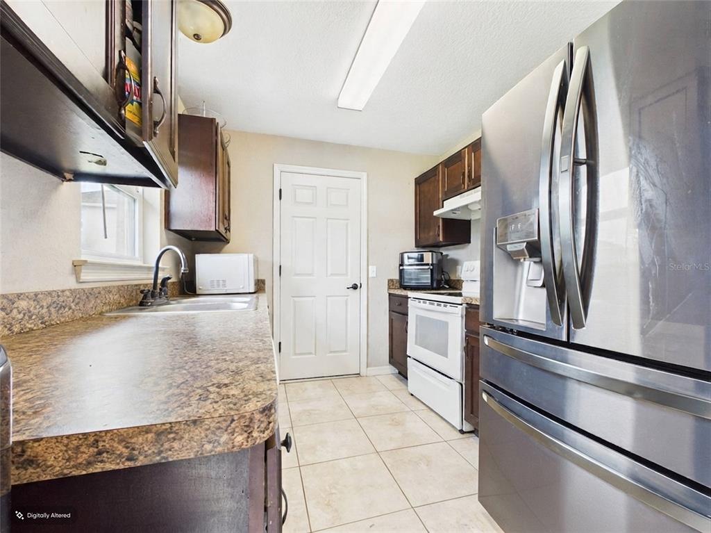 A kitchen features dark wood cabinets, laminate countertops, stainless steel appliances, and tile flooring — 15734 SW 46TH AVENUE ROAD, OCALA, FL