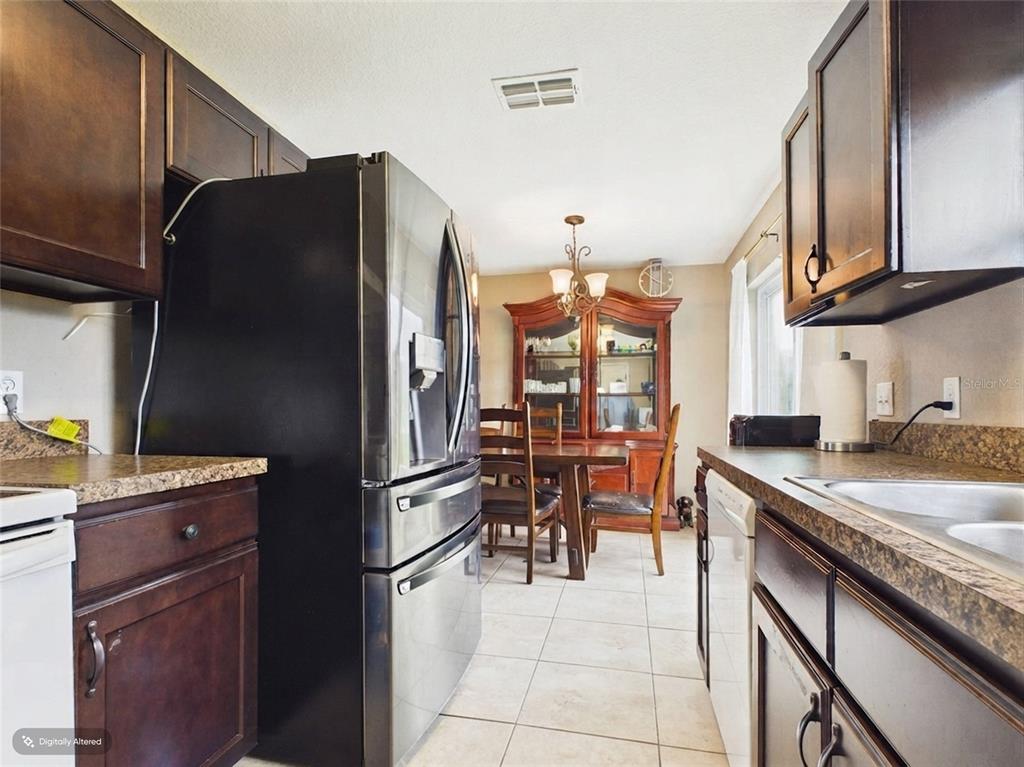 A kitchen with dark wood cabinets, stainless steel appliances, and an adjacent dining area — 15734 SW 46TH AVENUE ROAD, OCALA, FL