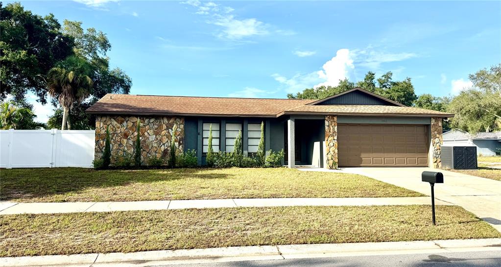 A brown front door with eight panels is set within a gray stucco entryway — 1861 WILLOW OAK DRIVE N, PALM HARBOR, FL