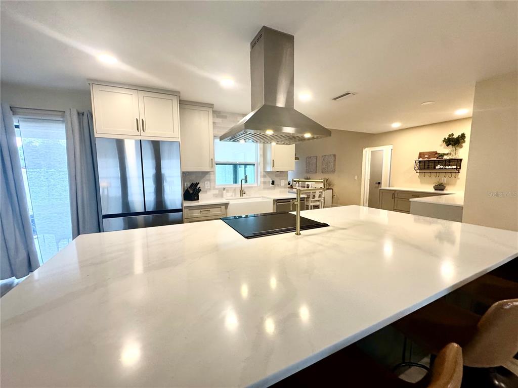 A kitchen with a large green island, bar stools, and light wood flooring — 1861 WILLOW OAK DRIVE N, PALM HARBOR, FL