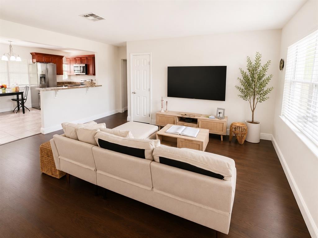 A living room with a beige sectional sofa, wood media console, and an open kitchen — 616 ELLENDALE DRIVE, WINTER PARK, FL