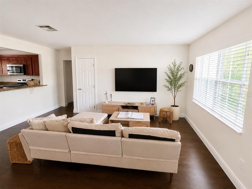 A living room features a beige sectional sofa, a television, and dark hardwood floors — 616 ELLENDALE DRIVE, WINTER PARK, FL
