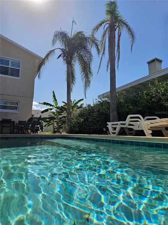 A swimming pool sits in front of a house with palm trees and lounge chairs — 2410 S ATLANTIC AVENUE, NEW SMYRNA BEACH, FL