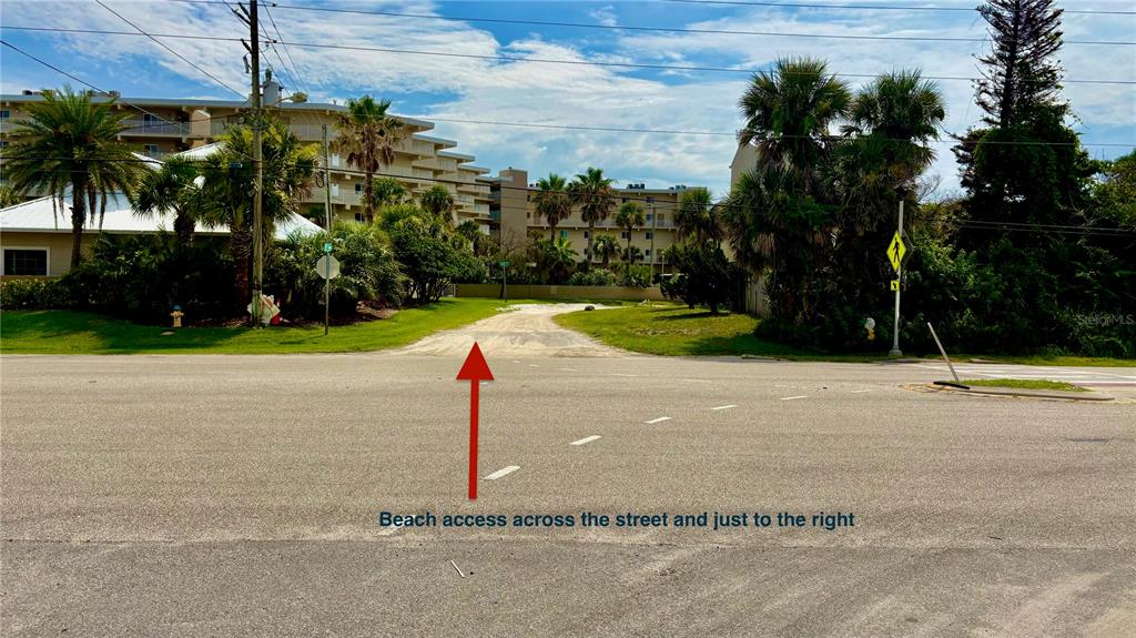 A paved road leads toward a sandy path between palm trees and apartment buildings — 2410 S ATLANTIC AVENUE, NEW SMYRNA BEACH, FL