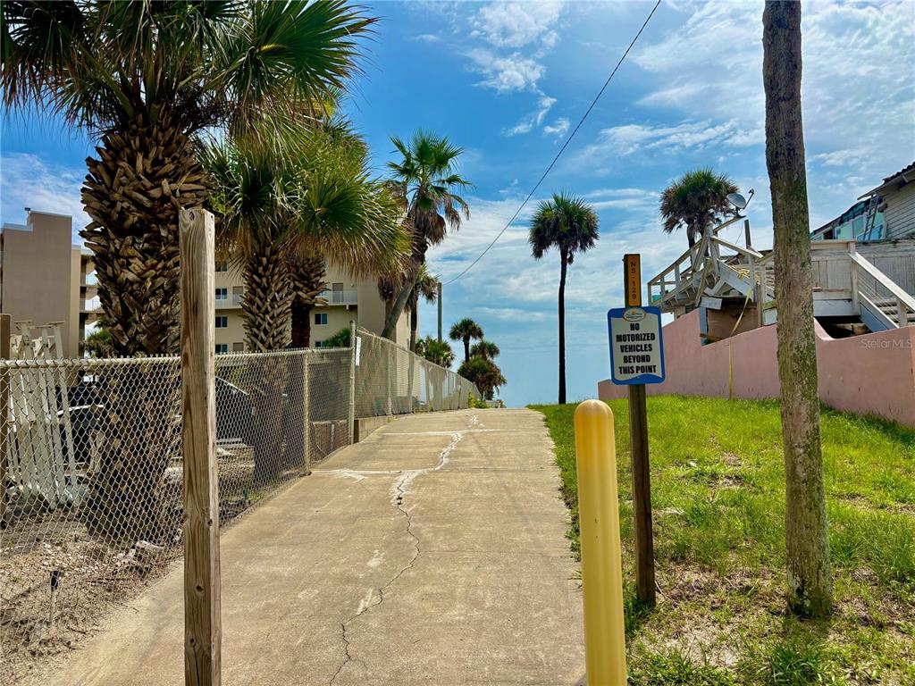 A concrete path leads toward the beach between a chain-link fence and a pink wall — 2410 S ATLANTIC AVENUE, NEW SMYRNA BEACH, FL