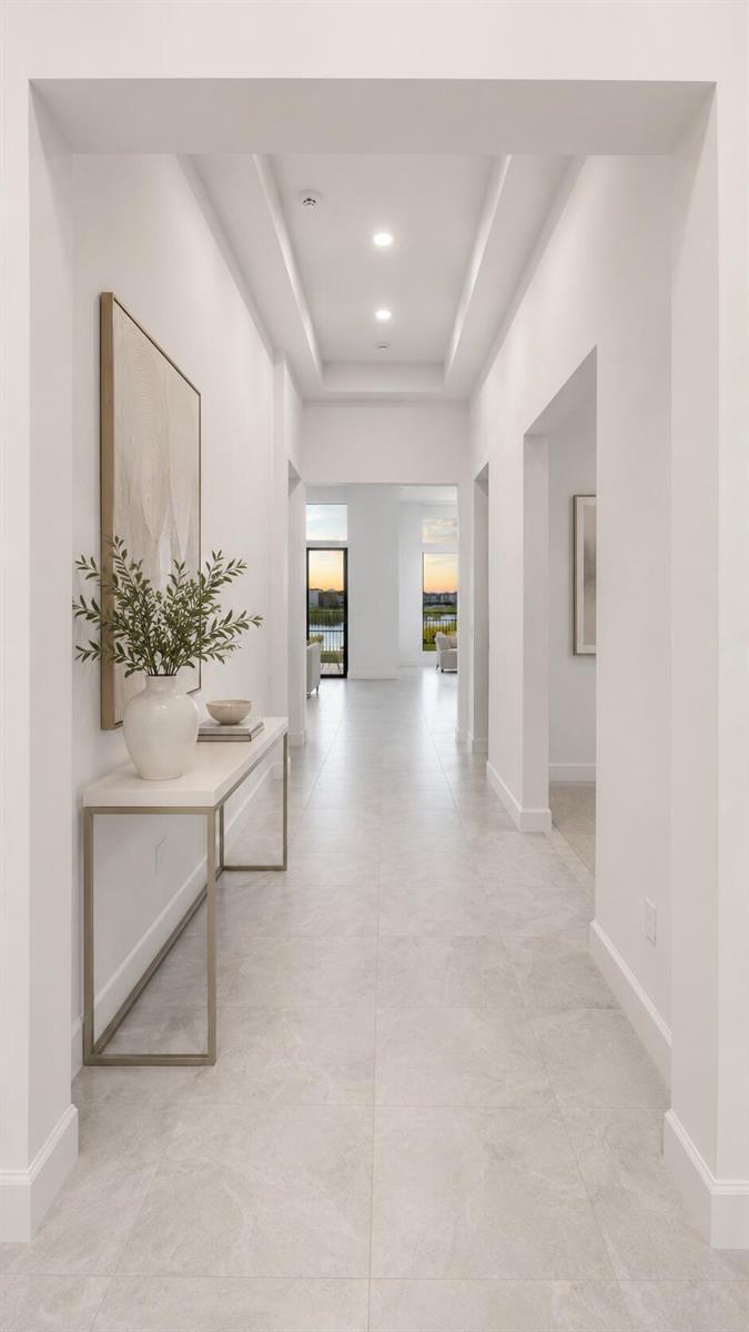 A bright, minimalist hallway features white walls, light tile flooring, and a modern console table — 9674 Spruce Woods Drive, Boynton Beach FL 33473, BOYNTON BEACH, FL