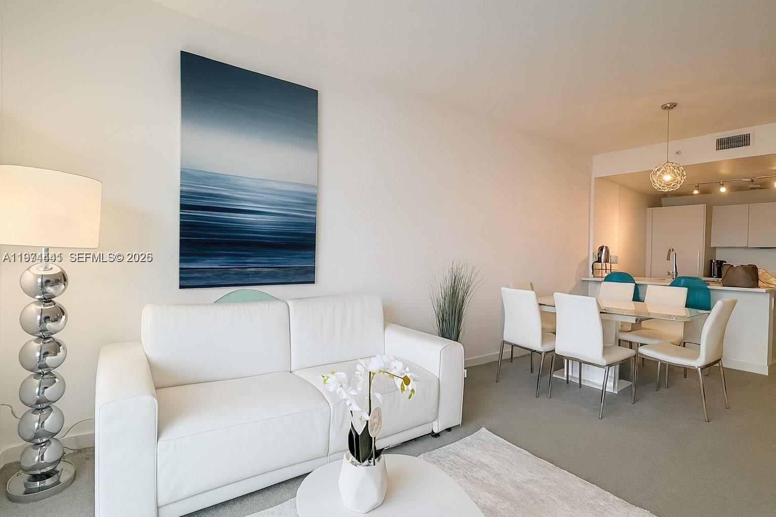 A living and dining area features a white sofa, a glass table, and blue artwork — 501 NE 31st St # 1204, Miami FL 33137, MIAMI, FL