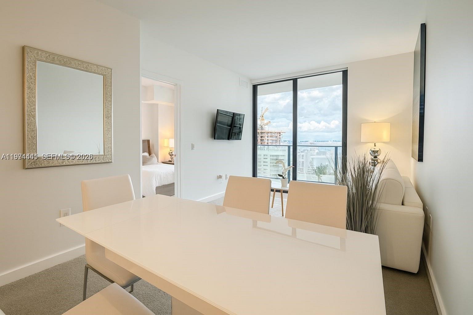 A dining area with a white table and chairs sits adjacent to a living space — 501 NE 31st St # 1204, Miami FL 33137, MIAMI, FL