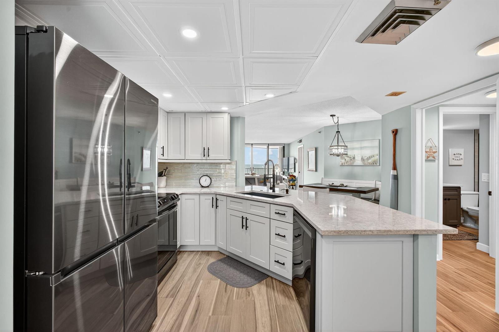 A kitchen features light gray cabinets, stainless steel appliances, and a peninsula with stone countertops — 9650 S Ocean Drive # 302, Jensen Beach FL 34957, JENSEN BEACH, FL