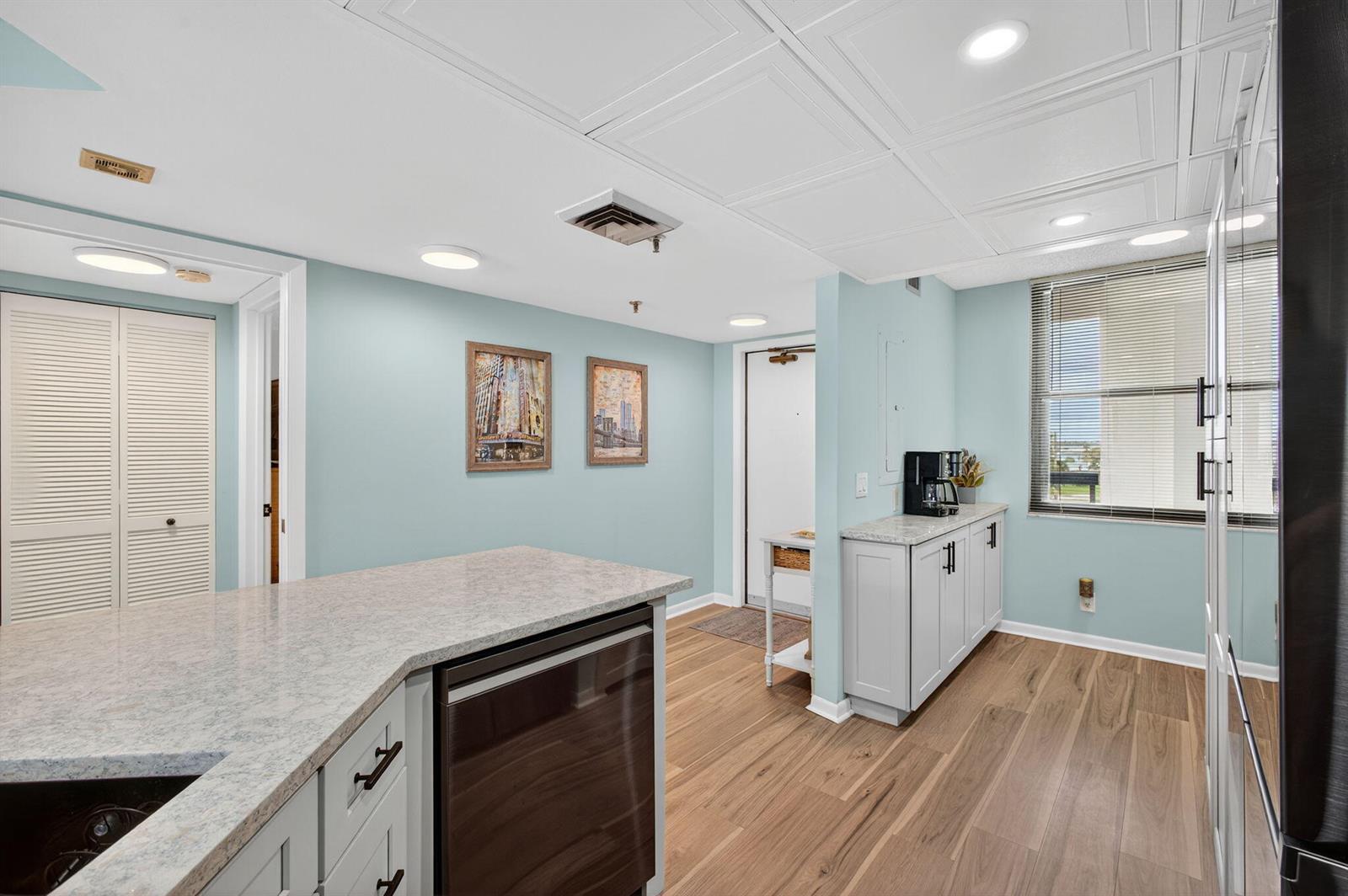 A kitchen with light blue walls, gray cabinets, granite countertops, and wood-look flooring — 9650 S Ocean Drive # 302, Jensen Beach FL 34957, JENSEN BEACH, FL