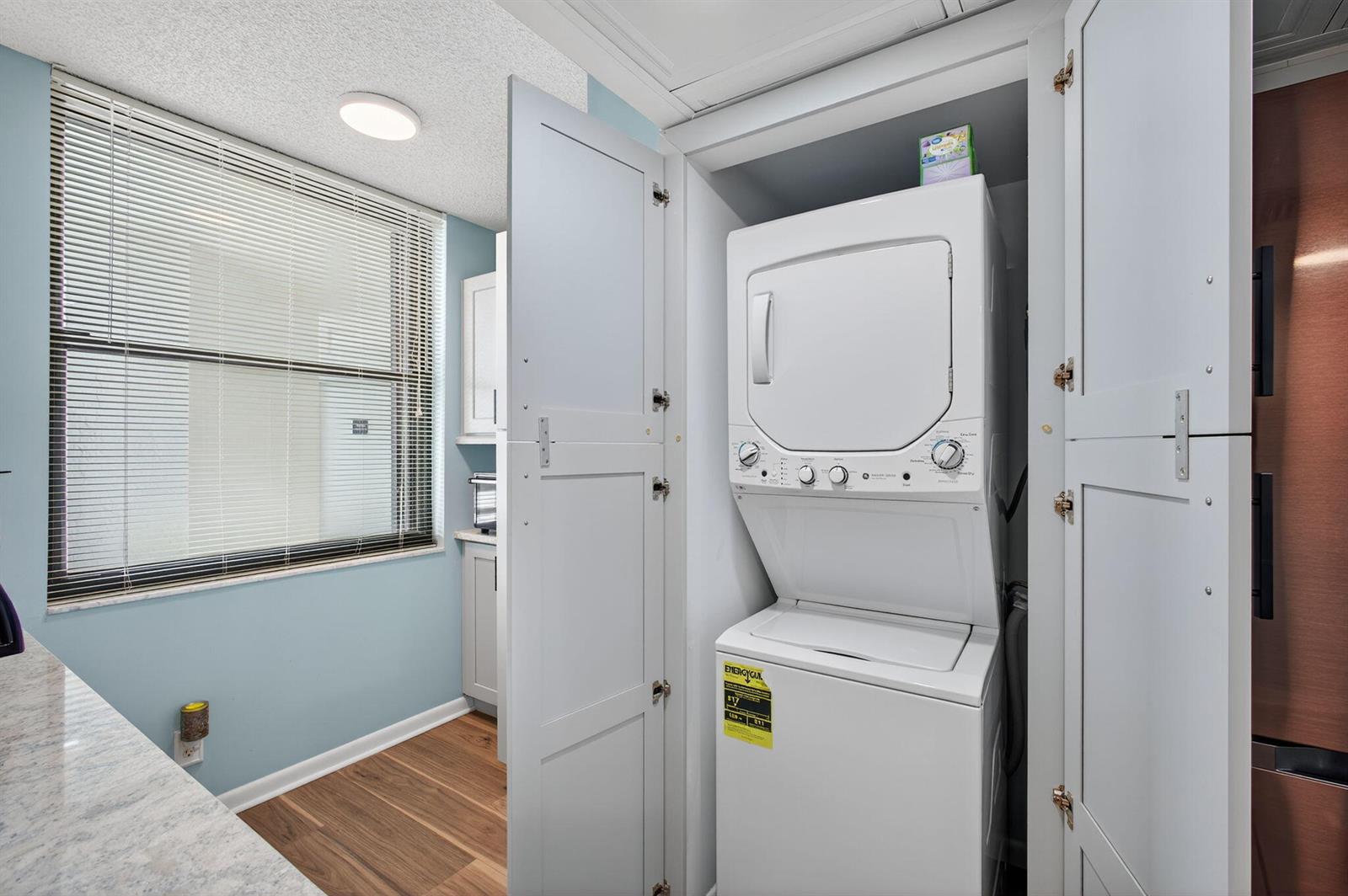 A laundry closet with a stacked washer and dryer sits in a room with light-blue walls — 9650 S Ocean Drive # 302, Jensen Beach FL 34957, JENSEN BEACH, FL