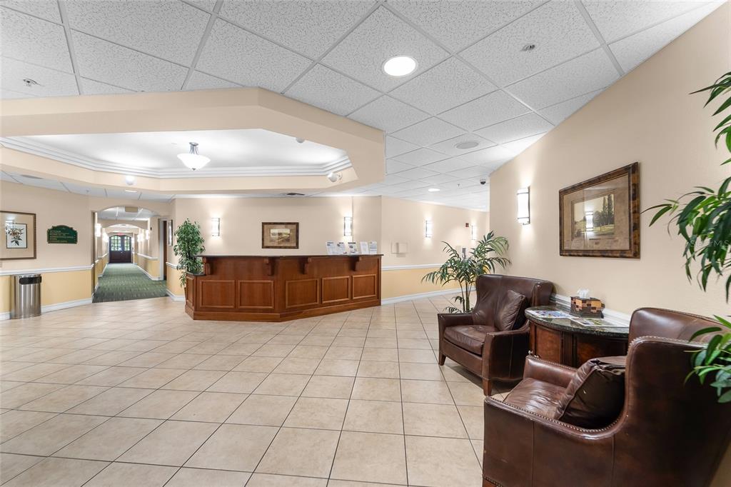 A lobby features a wooden reception desk, tile flooring, leather armchairs, and a drop ceiling — 13941 CLUBHOUSE DRIVE UNIT 106, TAMPA, FL