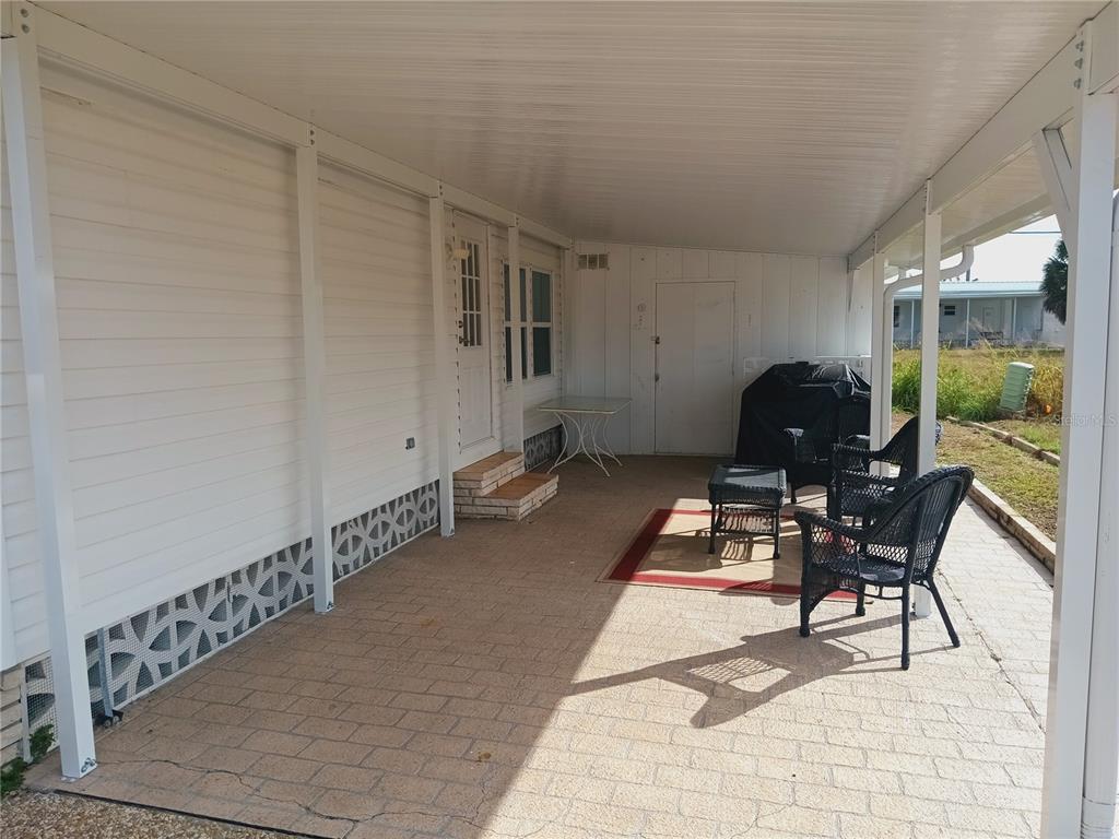 A covered patio with light-colored pavers, white siding, and outdoor furniture — 1580 BLIND BROOK DRIVE, SARASOTA, FL
